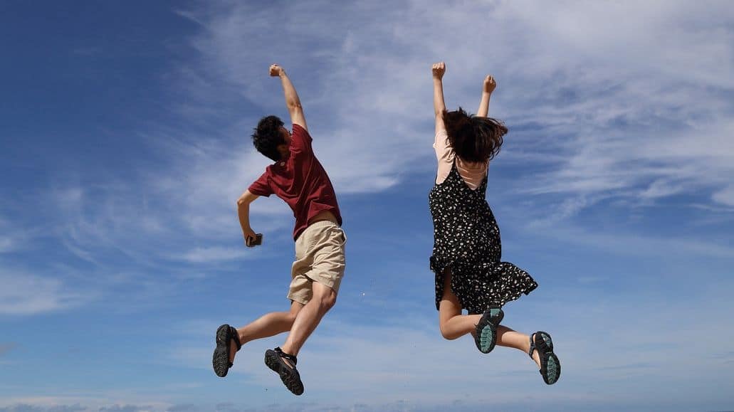 Two people jumping up tall and high