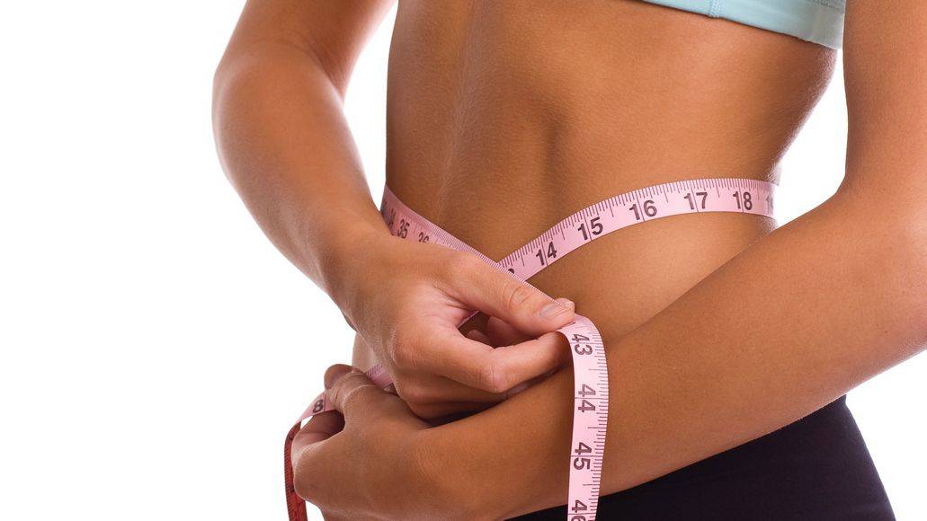 Woman using tape measure to see weight loss goals