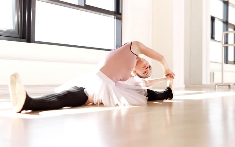 ballerina in leg warmers stretching